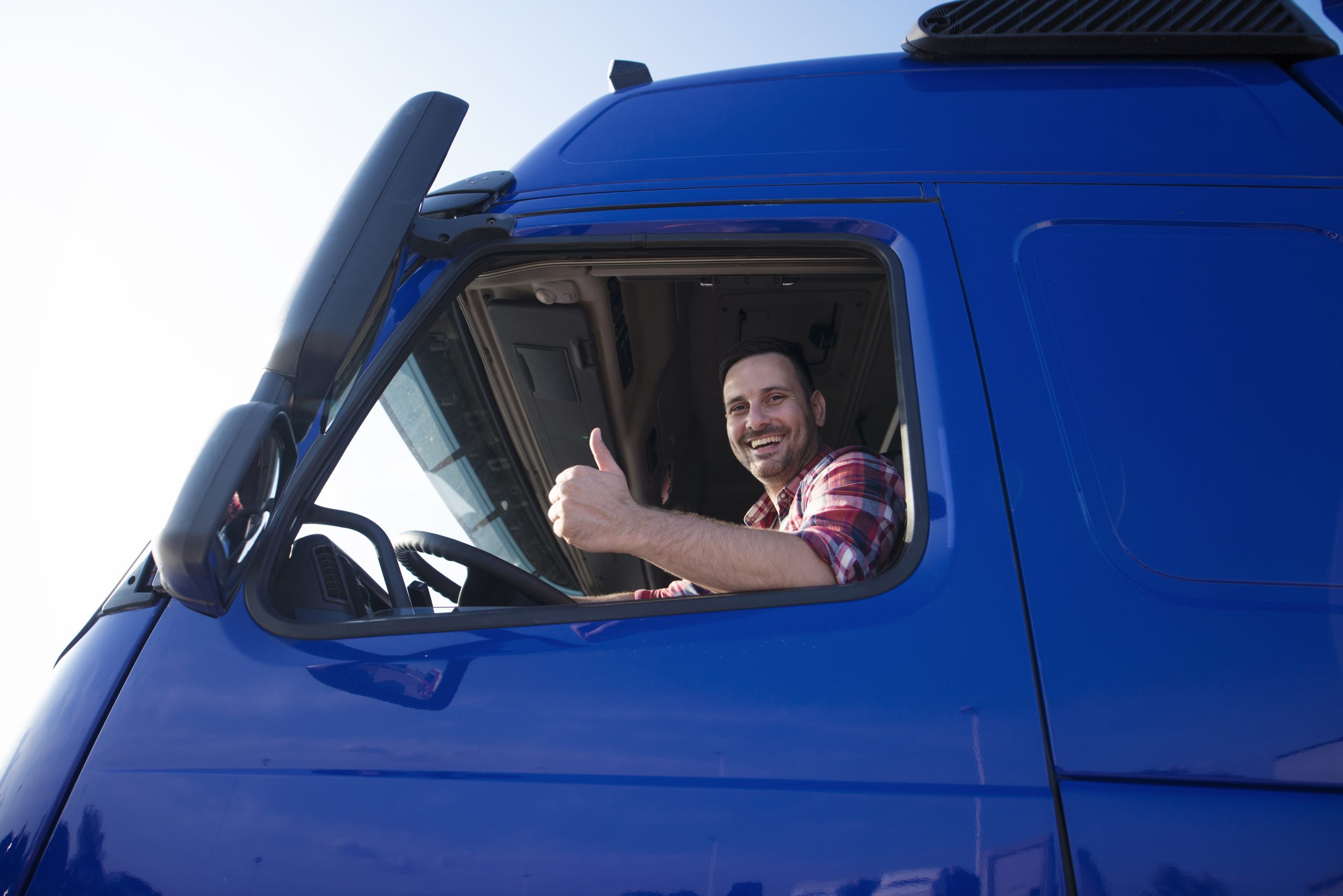 Truck driver showing thumbs up through cabin window.